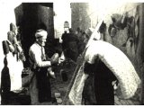 `Take up your Bed`. This Arab peasant pauses near the Damascus Gate to ask the price of a pair of shoes. He has bought a thin mattress stuffed with wool or cotton.